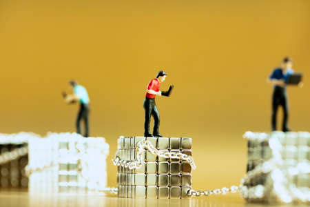 A concept of blockchain cryptocurrencies with man miniatures working with laptop against golden background.の写真素材