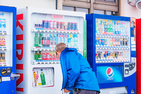 A man selecting a soft drink can from a vending machine in Rausu town. Taken in Hokkaido Island,...
