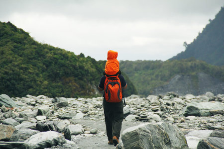 Very young asian boy carried by his father on his shoulders heading to Franz Josef Glacier in New...