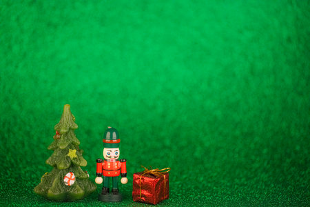 Generic toy of wooden nutcracker with Christmas trees and gifts on glitter green background