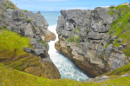 Pancake rocks in Punakaiki, New Zealand. The Pancake Rocks at Dolomite Point near Punakaiki are a heavily eroded limestone area where the sea bursts through several vertical blowholesの写真素材