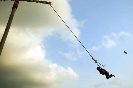 A man is flying circularly on a large pillar for his worship. At the time of mid April a festival of Hindu mythology and cultural origin ?GAJAN and CHADAK? is celebrated everywhere particularly in rural Bengal in India.のeditorial素材