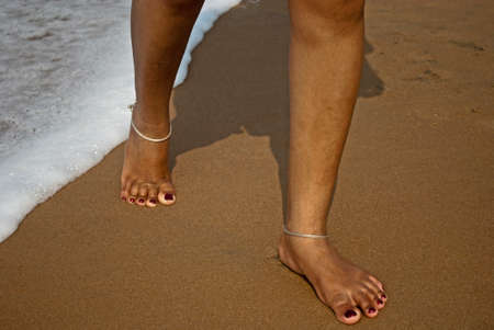 Legs of woman (girl) walking (jumping) on the water of sea on the beach. Close Up detail of female feet. Healthy lifestyle. Beach travel concept. Summer holiday. Outdoor.の写真素材