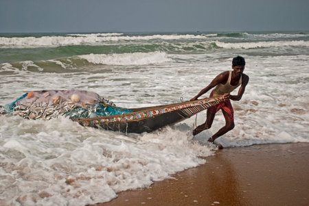 Fishing Boat: A fisherman is pulling a boat full with fish to sea beach at Puri, Orissa, Indiaのeditorial素材
