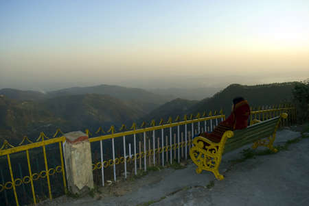 A tourist is enjoying the beauty of nature, sitting on a bench at the top view point of hill station Dalhousie, Himachal Pradesh, India.のeditorial素材