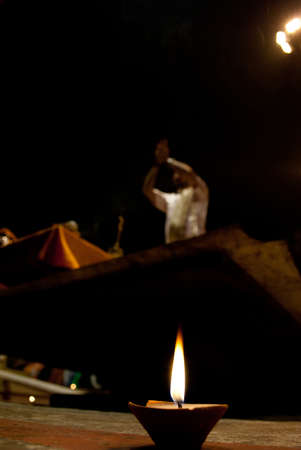 A hindu brahmin priest blows on a conch shell leading a night puja prayer ceremony on the Ganges river ghats in Varanasi, India.のeditorial素材