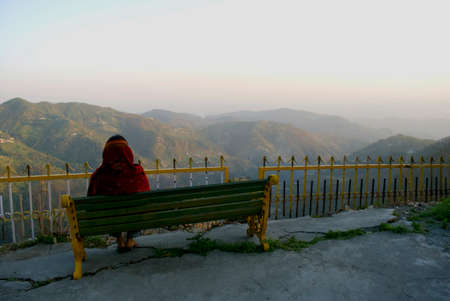 A tourist is enjoying the beauty of nature, sitting on a bench at the top view point of hill station Dalhousie, Himachal Pradesh, India.のeditorial素材