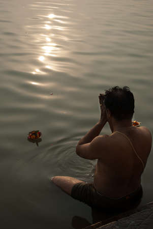 An Indian Hindu man is worshipping river Ganges after taking bath with meditation on the river Ganges at Varanasi, India.のeditorial素材