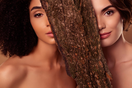 Photo of two attractive girls hide tree bark mystical fairytale nymphs flirt attract travelers in...