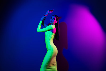 Profile portrait of confident tender model girl posing perfect shape empty space isolated on purple neon backgroundの写真素材