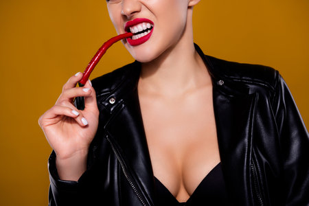 Cropped photo of aggressive lady leather jacket biting red hot chili pepper isolated on pastel brown color backgroundの写真素材