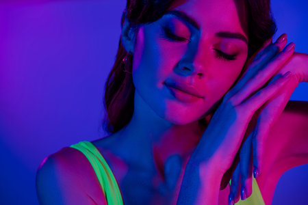 Close up photo of girl touch hands face glowing pink skin close eyes isolated vivid color backgroundの写真素材