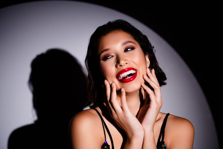 Portrait of lovely positive movie actress beaming smile arms touch face look empty space discotheque spotlightの写真素材