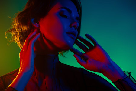 Photo of girl touch neck chin look aside with closed eyes isolated gradient neon color backgroundの写真素材