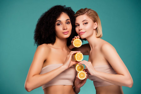 Photo of two girls hold lemon slices isolated over cyan color backgroundの写真素材