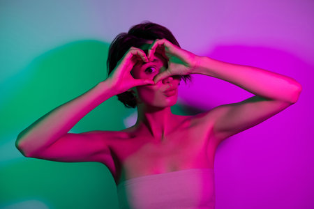 Photo of attractive girl make heart gesture look send air kiss isolated over vivid color backgroundの写真素材