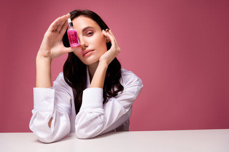 Photo of girl sit table cover face with serum liquid bottle isolated pastel color backgroundの写真素材