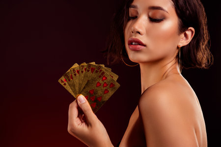 Photo of lovely rich lady showing cards combination playing poker game isolated on dark red color backgroundの写真素材