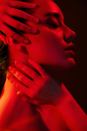 Cropped vertical photo of sexy tempting woman naked shoulders touch face isolated black red neon light backgroundの写真素材