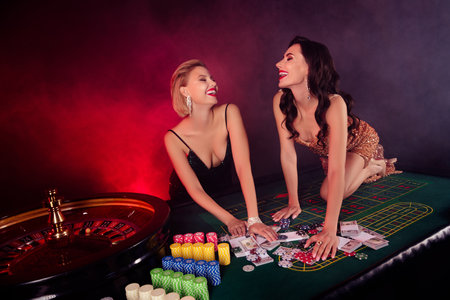 Photo of two adorable ladies wear dresses winning getting playing card christmas fortune isolated red fog backgroundの写真素材