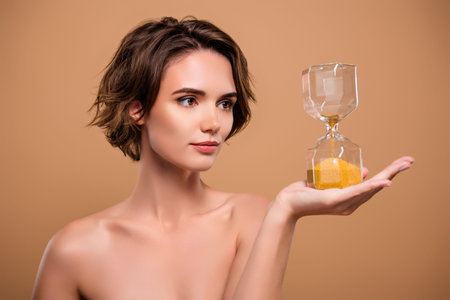 Photo of charming attractive lady nude shoulders holding hourglass isolated beige color background