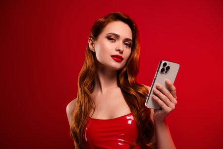 Photo of lovely attractive lady hold telephone eshop dressed sexy leather garment isolated on red color backgroundの写真素材
