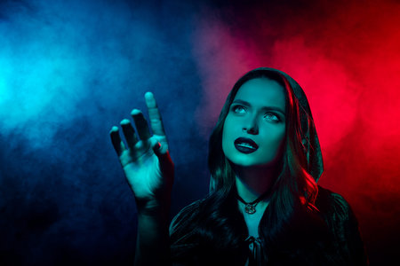 Photo of curious lady in witch wizard costume look up touch finger in neon filter mist background