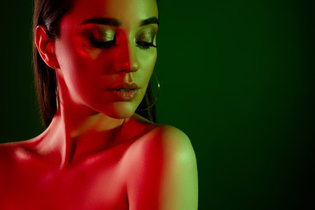 Close up cropped photo of stunning model girl make up earrings empty space colorful neon lights backgroundの写真素材