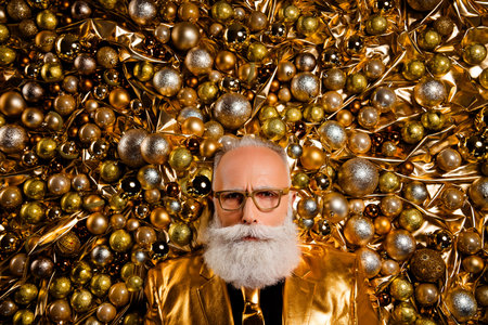 Top view portrait of extravagant man in glossy shiny costume tie look lying on christmas tree ornamentsの写真素材