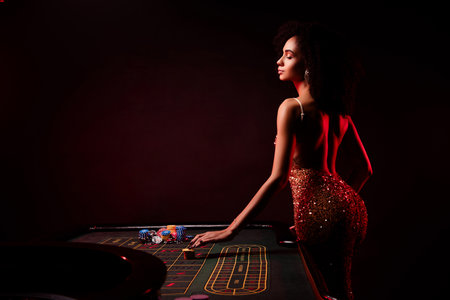 Photo of stunning charming lucky lady standing in professional poker private club on red neon backgroundの写真素材