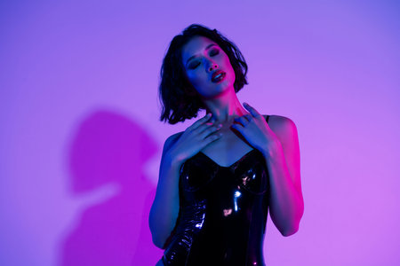 Photo of girl touch chest close eyes feel yempting isolated multicolor neon backgroundの写真素材