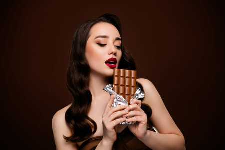 Photo of lovely gorgeous lady eat chocolate bar confectionery promo isolated on brown color...