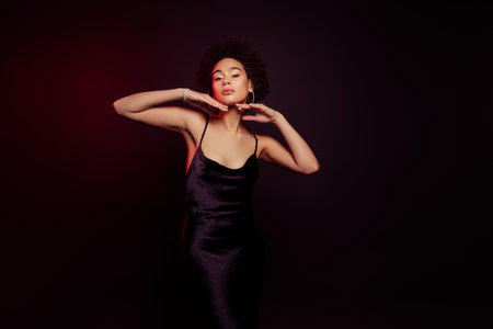 Photo of stunning model woman in black dress enjoy skin posing isolated on dark red color backgroundの写真素材