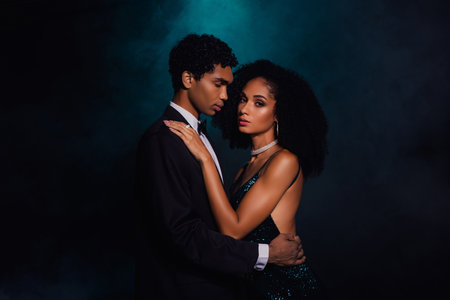 Elegant couple embraces against a dramatic black and green backgroundの写真素材
