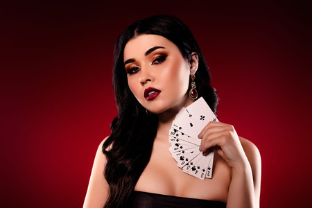 Portrait of lovely model woman show set poker cards isolated on dark burgundy background