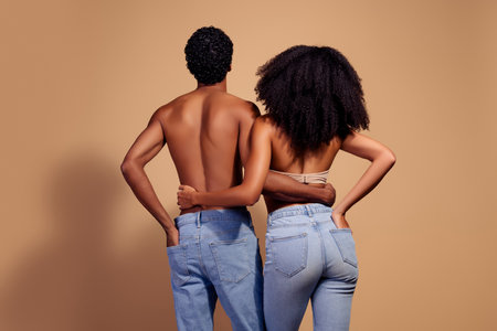 Young couple embracing in studio with beige background showcasing love and connection in stylish and intimate setting.の写真素材