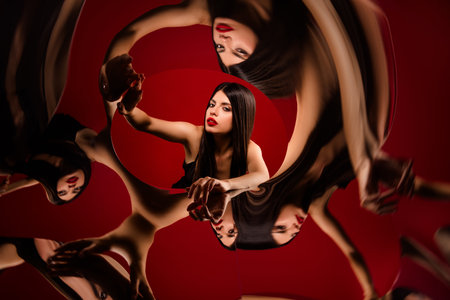 Captivating brunette woman surrounded by artistic reflections on a red backgroundの写真素材