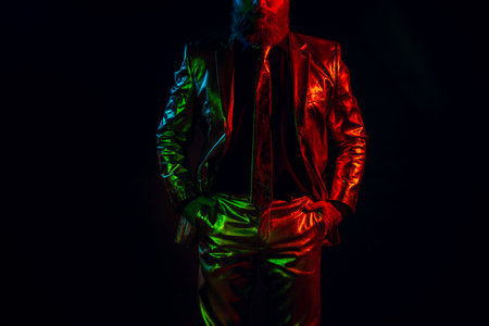 Chic gentleman in glossy colorful suit showcasing fashion elegance under glowing lightsの写真素材