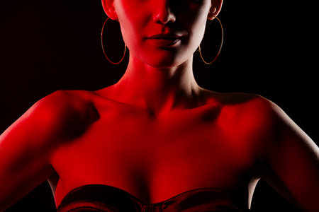 Cropped portrait of gorgeous model girl bare shoulders neon light isolated on black backgroundの写真素材