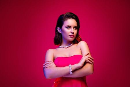 Confident young woman wearing pink dress, posing confidently against a gradient pink backgroundの写真素材