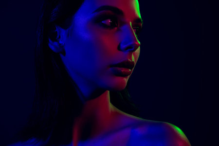 Stylish young woman in neon light with colorful illumination creating a vibrant and modern fashion conceptの写真素材