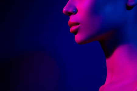 Side profile of a young woman illuminated by blue and pink neon light, blending modern fashion and club vibesの写真素材