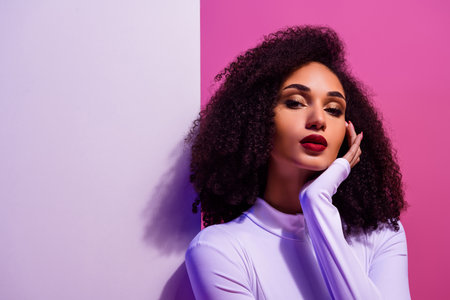 Beautiful young woman in a stylish outfit posing under neon lights with a colorful backgroundの写真素材