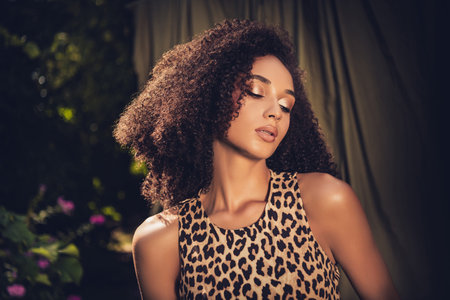 Portrait of a Young Woman in Leopard Pattern Dress with Curly Hair Posing Outdoors in Natural Light