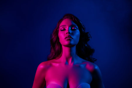 Sensual young woman in neon lighting showcasing beauty, sensuality, and glamour with a vibrant and stylish expression.の写真素材