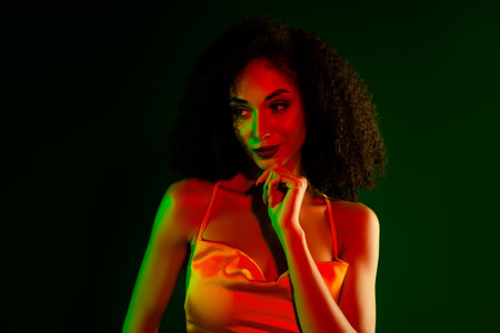 Elegant young woman in a vibrant lighting setup posing confidently in a stunning yellow cocktail dressの写真素材