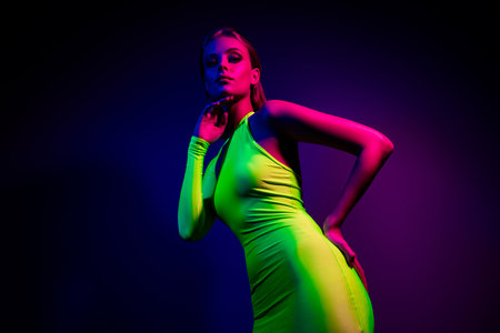 Stylish Young Woman in Neon Green Dress Posing Under Ultraviolet Pink and Blue Lights During a Club Partyの写真素材