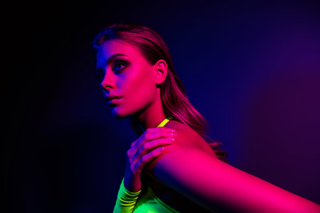 Stylish young woman posing in vibrant neon lights with a modern and trendy vibe, perfect for fashionの写真素材