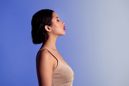 Portrait of a gorgeous rich woman in elegant pose against light blue studio background, exuding beautyの写真素材