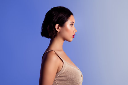 Mesmerizing portrait of a fashionable young woman with elegant makeup and hairstyle against a blue studio backgroundの写真素材